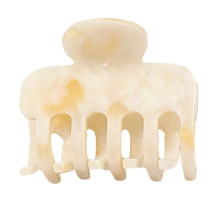 Anna Hårklemme - Cotton af Chris Rubin er et cremefarvet, marmoreret hårspænde med brede, buede takker og en afrundet top, vist på en almindelig hvid baggrund.