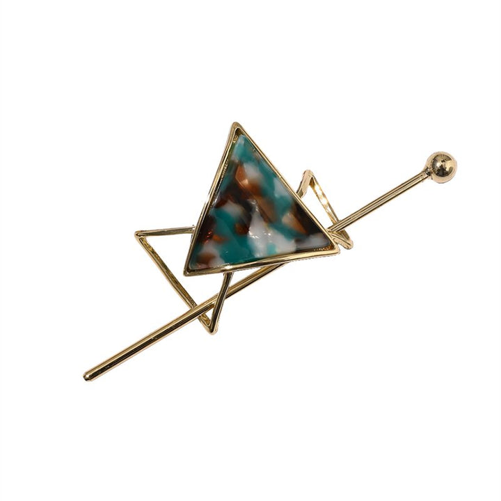 Løft din hårstyling med Cora Skydespænde | Jade af Chris Rubin - en geometrisk broche med en marmoreret blå, brun og hvid trekant indfattet i en guldramme med krydsende linjer og en lille guldkugle.