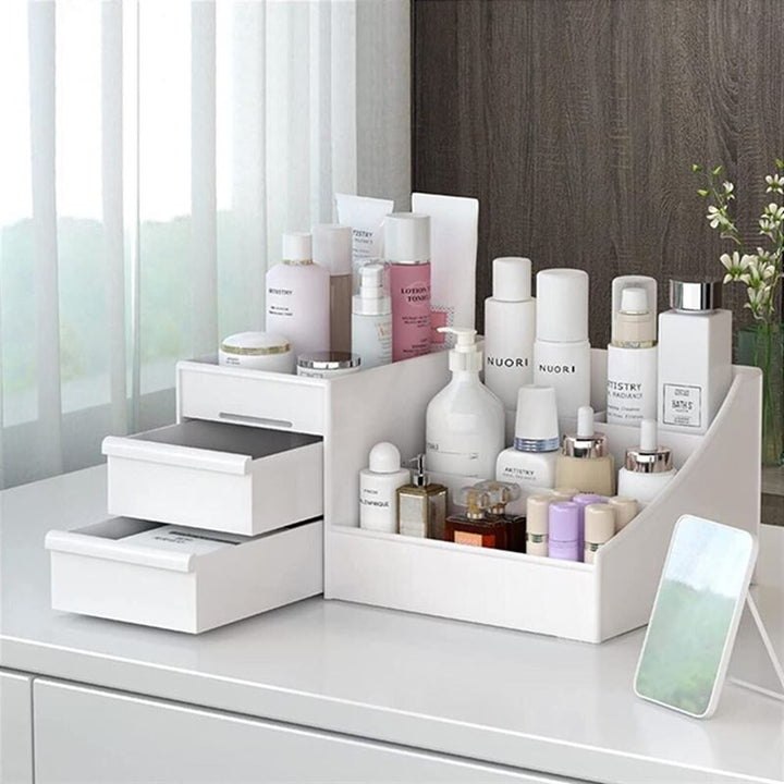 UNIQ Kosmetik Organizer | P110 | Hvid fra UNIQ opbevarer pænt hudpleje og kosmetik med skuffer og rum. Den står på en hvid bordplade ved et vindue med et lille spejl foran.
