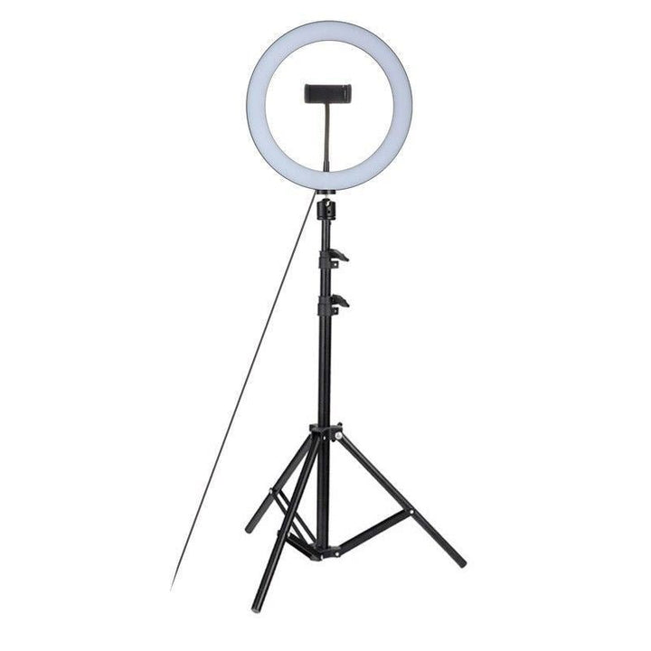 UNIQ Pro Ringlight Studio fra UNIQ: Sort ringlys på stativ med telefonholder i midten og kabelstrøm, perfekt til billeder/videoer - vist mod hvid baggrund.