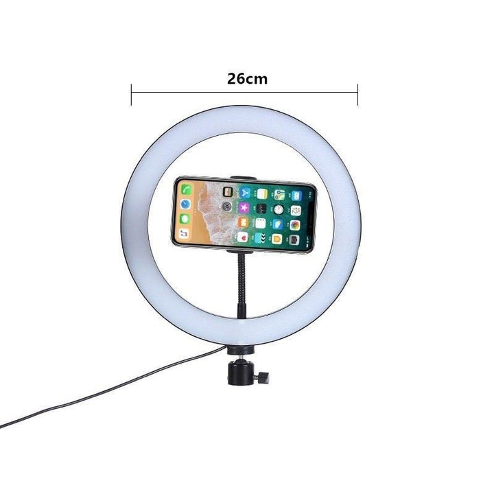 UNIQ Pro Ringlight Studio fra UNIQ er en 26 cm ringlight med professionelt lys og telefonholder i midten, monteret på stativ. Strøm tilføres via synligt kabel fra basen - perfekt til billeder og videoer.