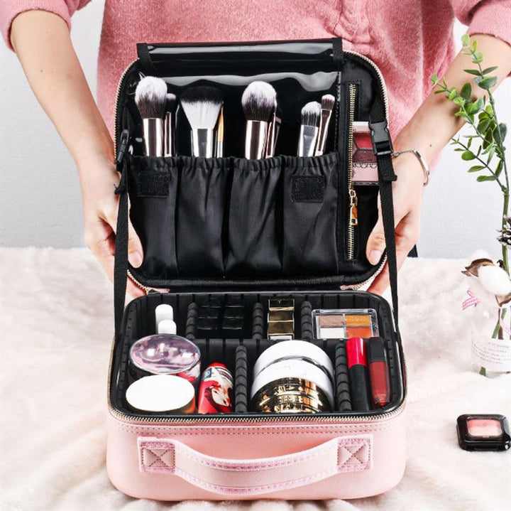 En person holder UNIQ Rejsetoilettaske / Kosmetiktaske til alt dit Makeup | Pink fra UNIQ, pænt organiseret med børster, kompakter, læbestifter og krukker i elastiske åbninger og separate rum til perfekt opbevaring.