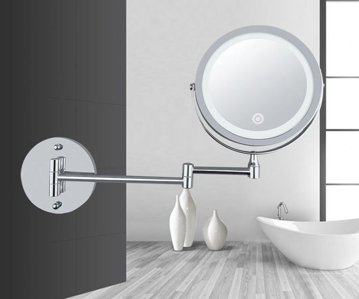 UNIQ Vægmonteret LED Kosmetikspejl med justerbar, rund form, leddelt arm og forstørrelse fra UNIQ hænger i det moderne badeværelse med hvidt badekar, dekorative vaser og trægulv. Perfekt som makeupspejl.