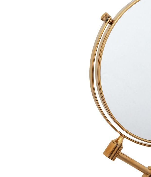 Et nærbillede af UNIQ Vægspejl med x10 Forstørrelse | Guld fra UNIQ med den runde, gyldne ramme og stativ, hvor en del af spejlet er synligt mod en almindelig, lys baggrund.