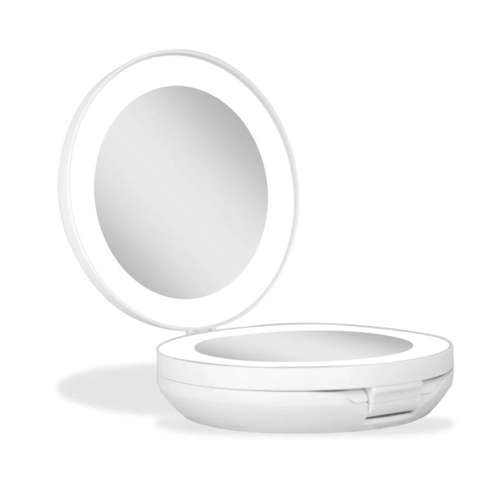 UNIQ Kompakt dobbelt rejsespejl med LED (10x forstørrelse) – Hvid vises i åben tilstand, hvilket fremhæver den blanke, reflekterende overflade og det glatte, runde design med et hængslet låg. Dette elegante, kompakte spejl fra UNIQ har 10x forstørrelse og indbygget LED-belysning, hvilket gør det ideelt til præcise retoucheringer. Produktet er fotograferet på en ensfarvet hvid baggrund.