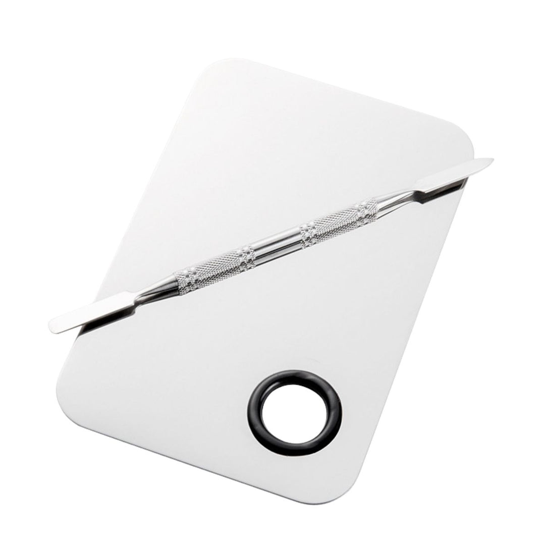 Technique PRO Professional Makeup Mixing Palette, der er fremstillet af rustfrit stål med afrundede kanter og et praktisk cirkulært tommelfingerhul i det ene hjørne, leveres sammen med en blandespatel af metal, der ligger diagonalt hen over den rektangulære overflade – perfekt til nem udjævning af foundation.