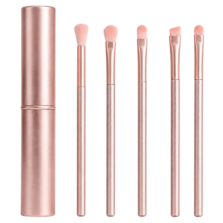 Et sæt bestående af fem lyserøde UNIQ Technique PRO Rose Lens øjenskyggebørster med matchende skafter er pænt anbragt ved siden af et stilfuldt, rosaguld cylinderetui, alt sammen præsenteret på en hvid baggrund. Dette elegante sæt er perfekt til at skabe fejlfri makeup-looks.