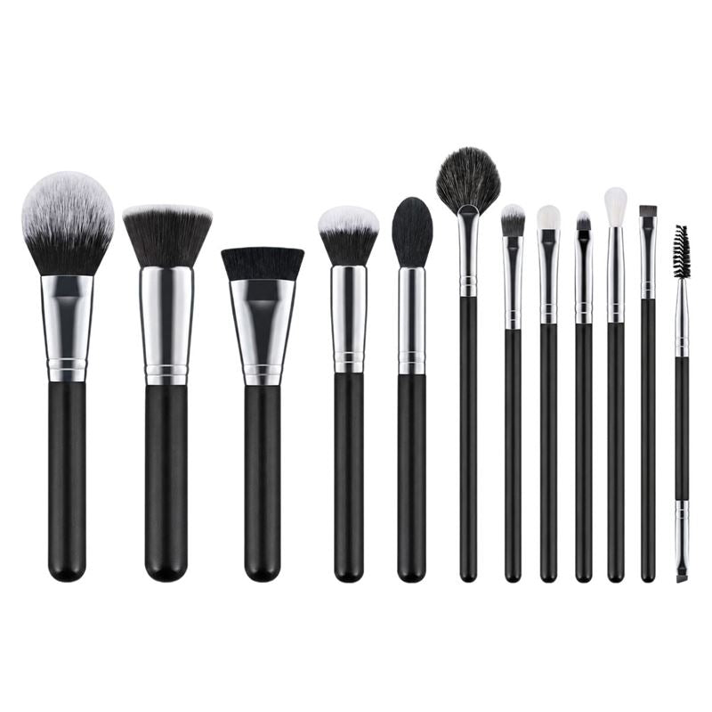 Technique PRO Galactic Ray Makeupbørste Sæt – 12 makeupbørster fra Technique PRO består af tolv børster med sorte skafter og sølvfarvede metalringe, hvor hver enkelt har en unik form og størrelse, der sikrer alsidig anvendelse – herunder ansigtsbørster og øjenbørster – og præsenteres elegant på række på en hvid baggrund.