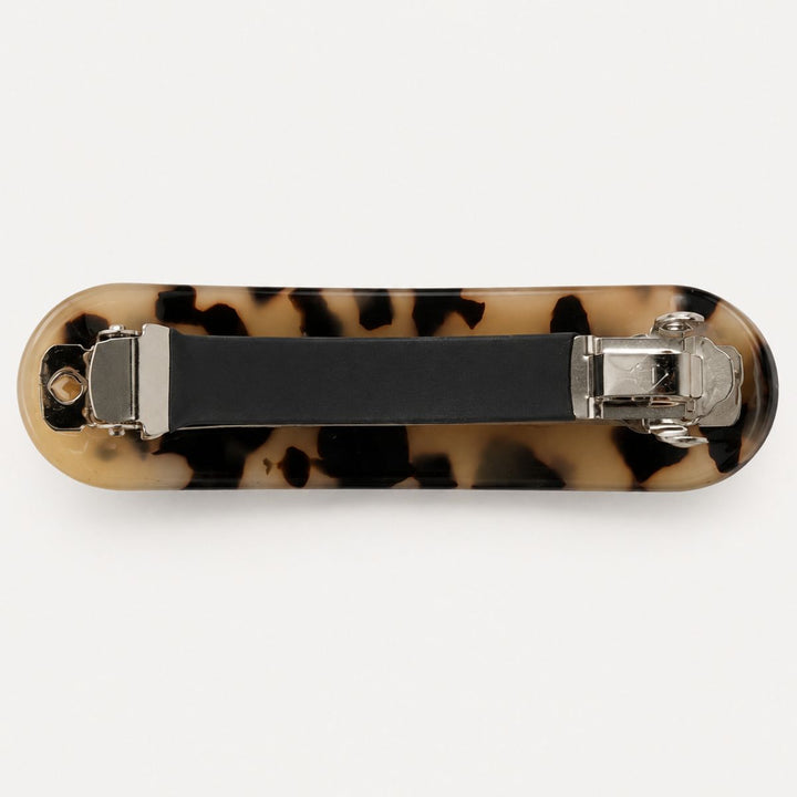 SOHO Mila Barrette Hårspænde – Light Tortoise fra SOHO har et rektangulært design med et stilfuldt mønster i lys skildpaddemønster og en holdbar kliklås af metal på bagsiden, her afbilledet på en hvid baggrund.