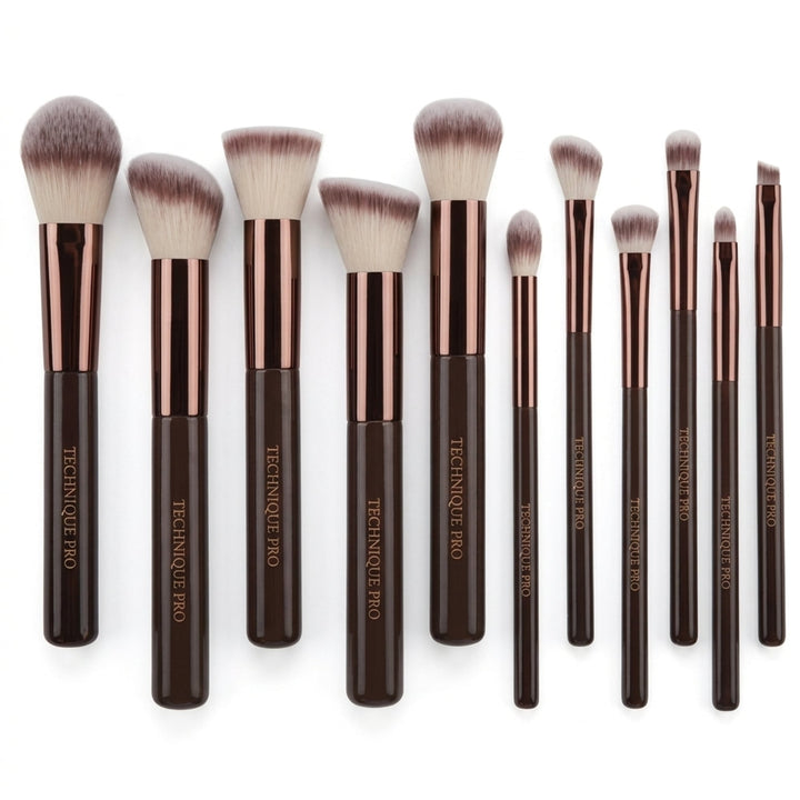 Et sæt bestående af elleve Technique PRO Chocolate Bronze Makeupbørste Sæt – 11 makeupbørster med brune skafter og metalliske hylster, anbragt på række.