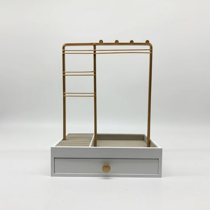 UNIQ Smykkestativ / Smykkeskrin i Guld med Skuffe er en stilfuld hvid smykkeopbevaring fra UNIQ. Den består af et elegant smykkestativ i guldmetal til ophængning af øreringe, ringe og halskæder samt en lille bakke og en skuffe i bunden prydet med en rund guldknap – alt sammen på en enkel hvid baggrund.