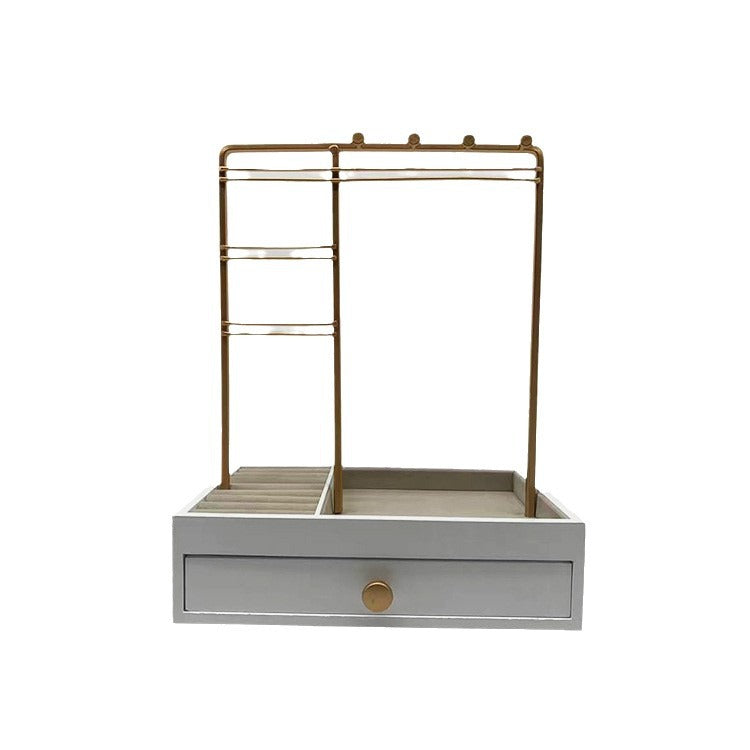 Oplev elegant opbevaring af smykker med UNIQ Smykkestativ / Smykkeskrin i guld med skuffe – Holder til øreringe, ringe og kæder (29 cm) fra UNIQ. Denne hvide opbevaringsløsning har en elegant guldmetalramme, flere rum til ringe, halskæder og andet tilbehør samt en enkelt skuffe i bunden med en rund guldknap – et perfekt eksempel på smykkeopbevaring til dine yndlingssmykker.